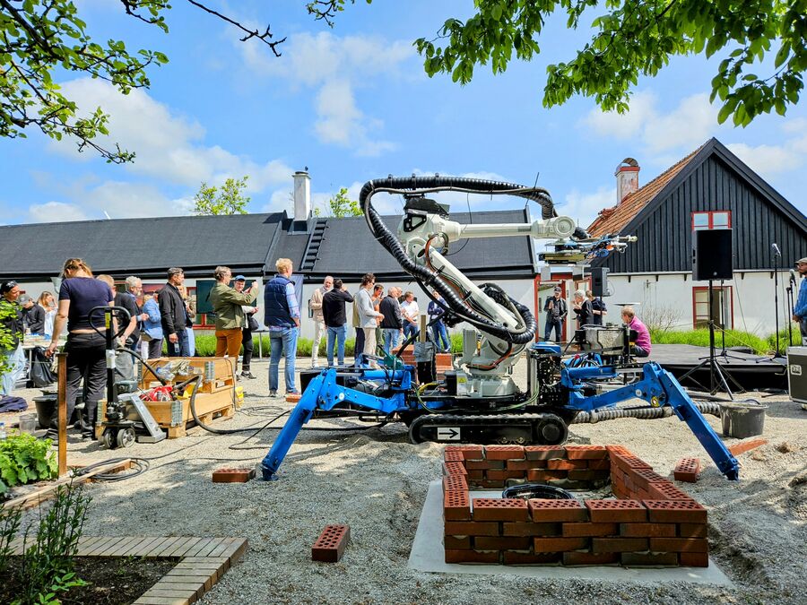 The mobile construction robot with capactity for identifying, gripping and placing bricks, with integrated nozzle for mortar deposition.